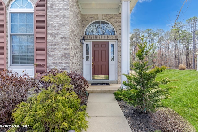 doorway to property featuring brick siding and a yard