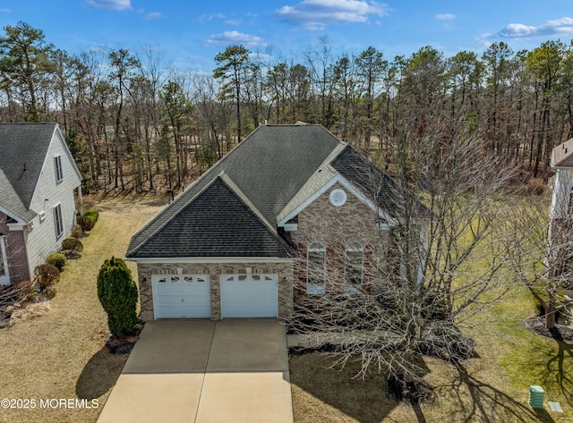 view of front of house with driveway, an attached garage, and roof with shingles