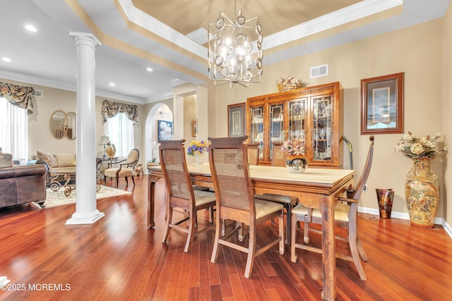 dining space featuring visible vents, a raised ceiling, an inviting chandelier, and ornate columns