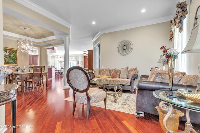 living area featuring a notable chandelier, wood finished floors, ornate columns, and ornamental molding