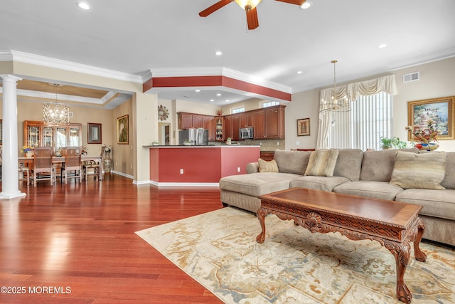 living room with a wealth of natural light, visible vents, dark wood-type flooring, and decorative columns