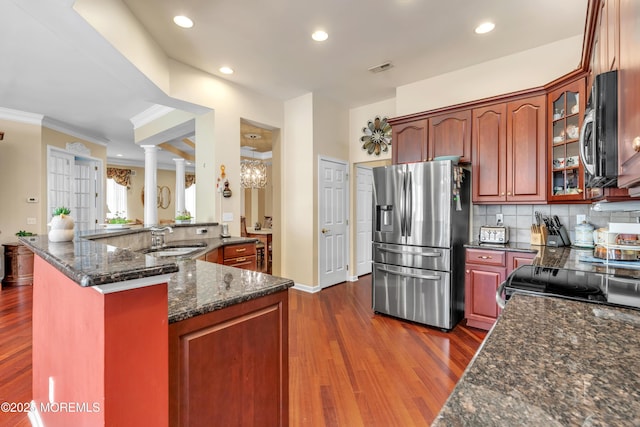 kitchen with dark wood-type flooring, a sink, backsplash, appliances with stainless steel finishes, and glass insert cabinets