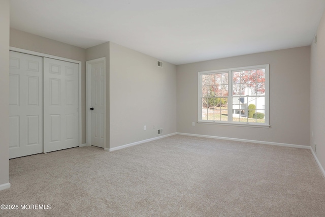 unfurnished bedroom featuring a closet, visible vents, baseboards, and carpet floors