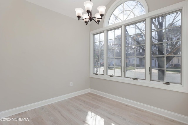 unfurnished room with baseboards, light wood-style floors, and a chandelier