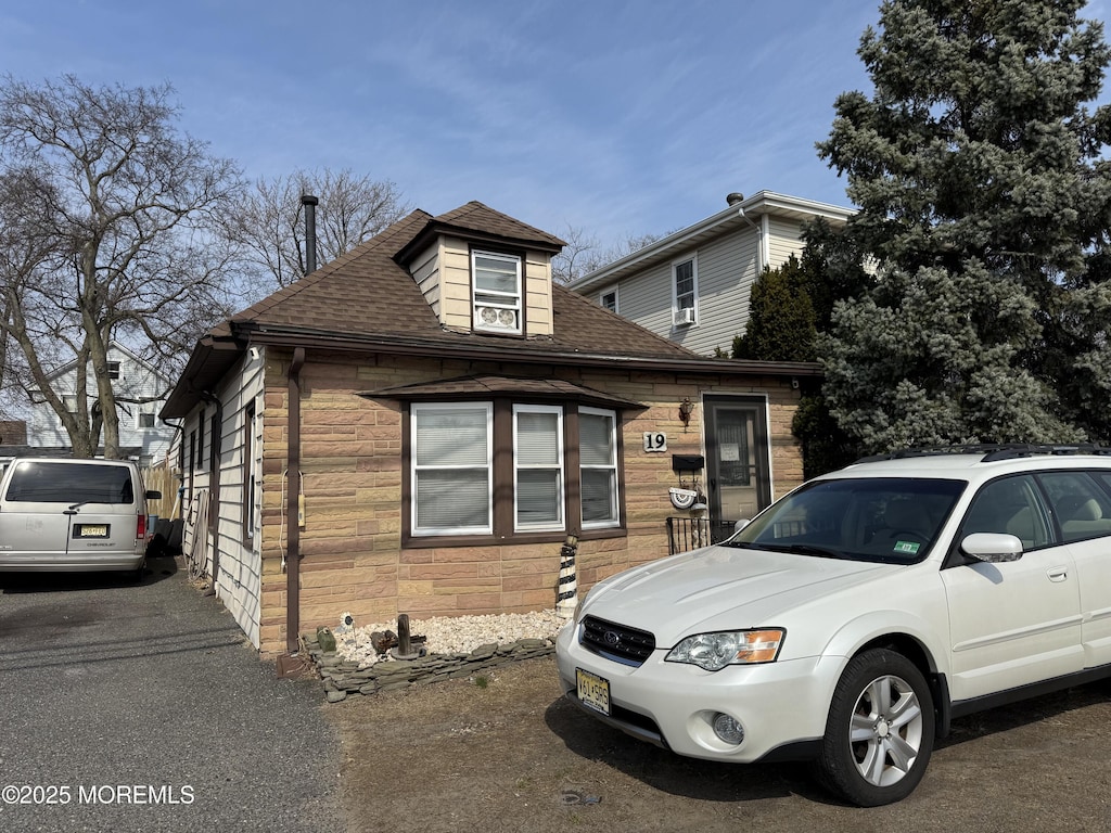 view of front of house with stone siding and roof with shingles