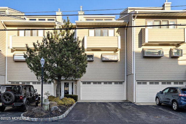 view of building exterior featuring driveway, a wall mounted AC, and a garage