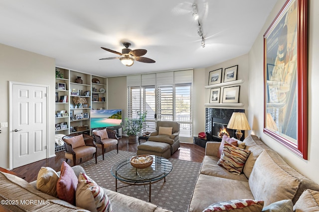 living room featuring a fireplace, rail lighting, a ceiling fan, and wood finished floors