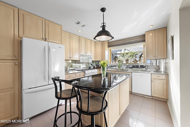 kitchen with visible vents, light brown cabinets, a breakfast bar, light tile patterned floors, and white appliances