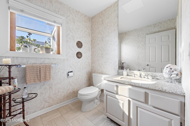 bathroom featuring vanity, toilet, and baseboards