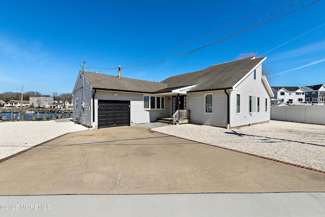 view of front of house featuring driveway, a shingled roof, a garage, and fence