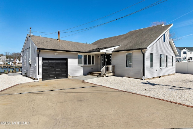 ranch-style house with concrete driveway, fence, a garage, and roof with shingles