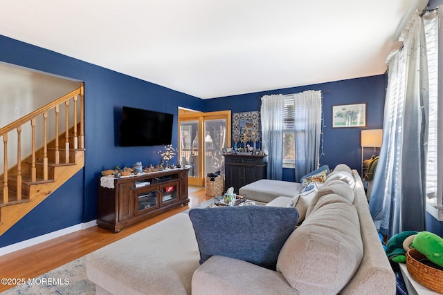 living area with stairs, baseboards, and wood finished floors