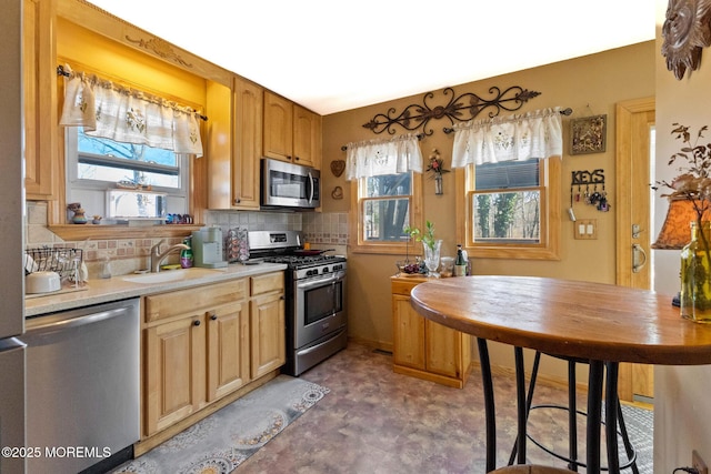 kitchen featuring backsplash, stainless steel appliances, light countertops, and a sink