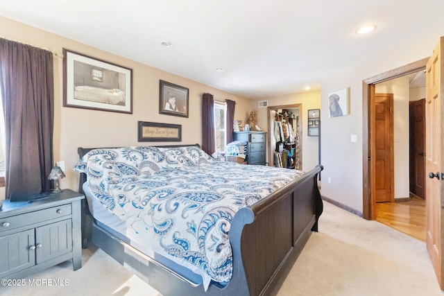 bedroom featuring a spacious closet, visible vents, baseboards, light carpet, and recessed lighting