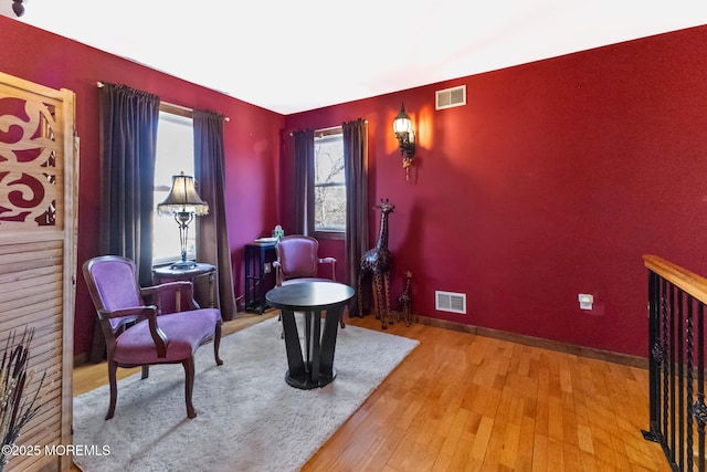 sitting room with wood finished floors, visible vents, and baseboards