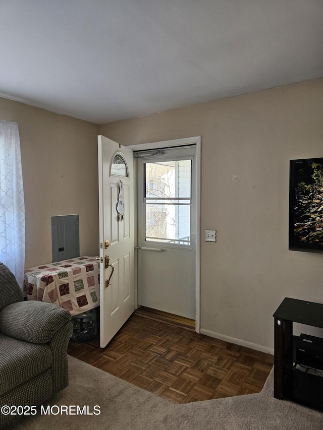 foyer entrance with electric panel and baseboards