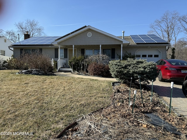 ranch-style house with driveway, a porch, a front yard, a garage, and solar panels