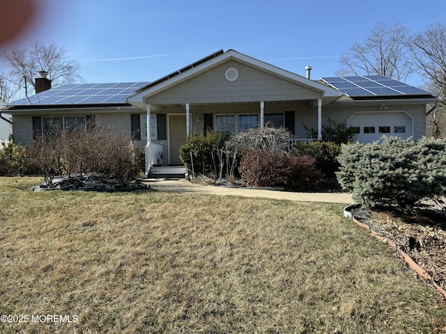 single story home with a porch, roof mounted solar panels, an attached garage, and a front lawn