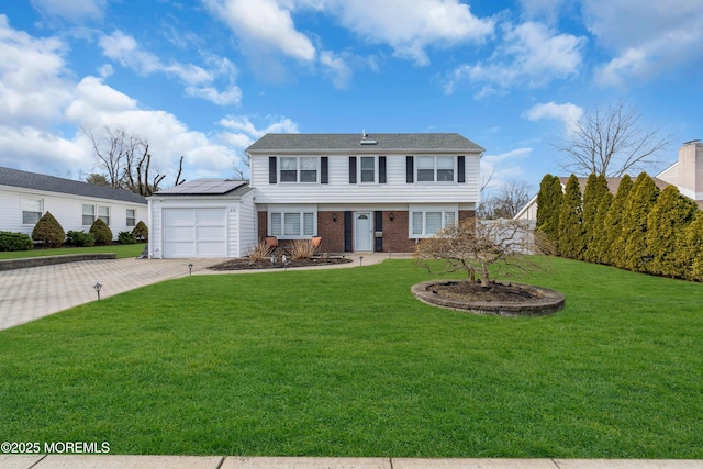 colonial-style house featuring a garage, a front lawn, decorative driveway, and brick siding