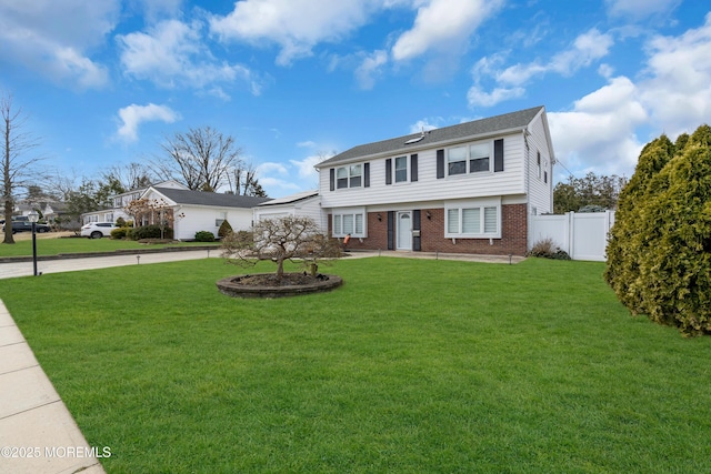 colonial inspired home featuring a front yard, brick siding, driveway, and fence