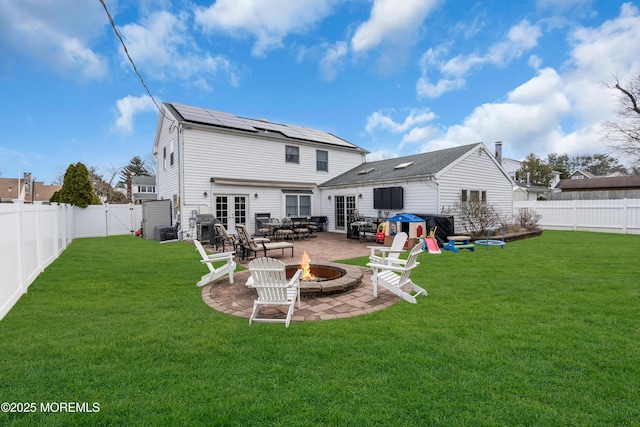 rear view of house with a fire pit, a lawn, french doors, a fenced backyard, and a patio