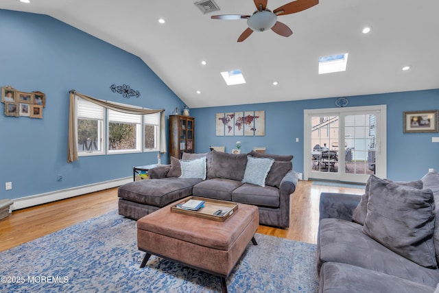 living area with lofted ceiling with skylight, a healthy amount of sunlight, visible vents, and a baseboard radiator