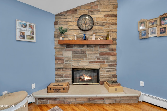 interior details with baseboard heating, a stone fireplace, a baseboard heating unit, and wood finished floors