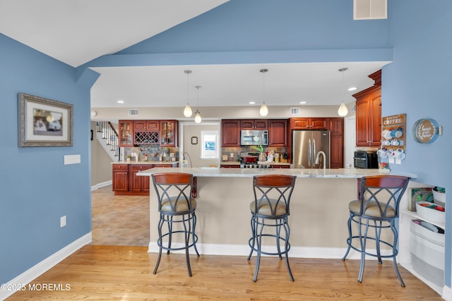 kitchen with a breakfast bar area, stainless steel appliances, visible vents, and a peninsula