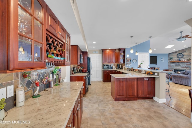 kitchen featuring light stone counters, a breakfast bar, a peninsula, decorative backsplash, and open floor plan