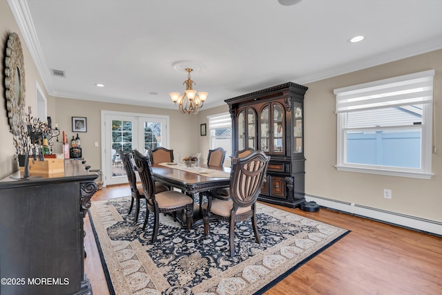 dining space featuring a chandelier, visible vents, wood finished floors, and crown molding