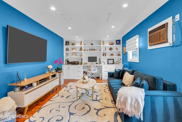 living area featuring built in shelves, an AC wall unit, wood finished floors, recessed lighting, and built in study area