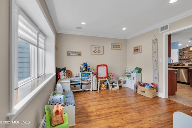 rec room featuring visible vents, recessed lighting, a sink, crown molding, and light wood-type flooring