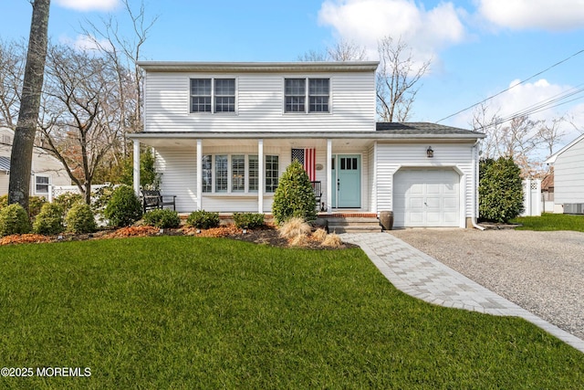 traditional home with a porch, an attached garage, driveway, and a front yard