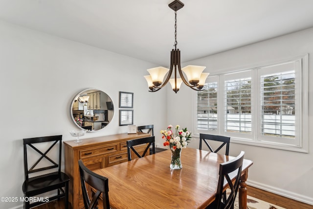 dining room with baseboards, an inviting chandelier, and wood finished floors