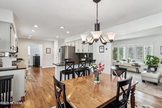 dining space featuring a notable chandelier, recessed lighting, baseboards, and wood finished floors