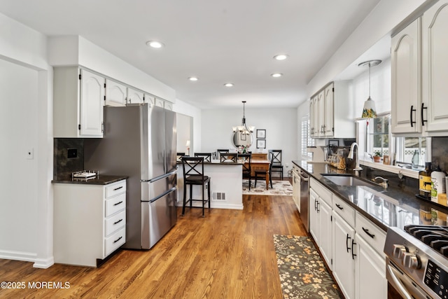 kitchen with a sink, stainless steel appliances, light wood-style flooring, and white cabinets