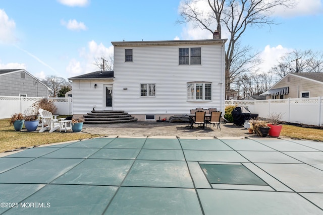 rear view of property with a patio area, a fenced in pool, a chimney, and entry steps