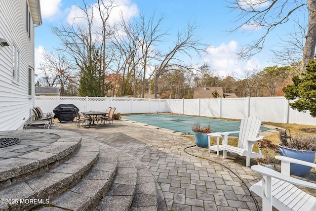 view of patio featuring outdoor dining space, a fenced backyard, a fenced in pool, and a grill