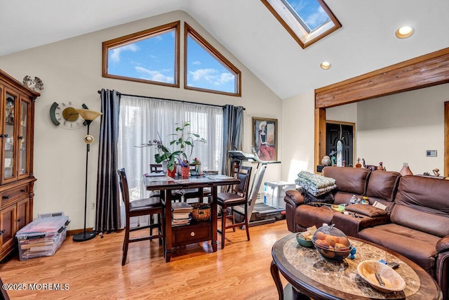 living area with recessed lighting, light wood-style flooring, high vaulted ceiling, and a skylight