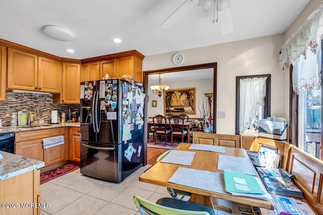 kitchen with black appliances, ceiling fan with notable chandelier, a sink, light tile patterned flooring, and decorative backsplash