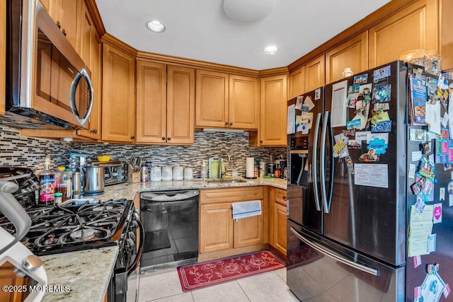 kitchen featuring a sink, black dishwasher, gas range, stainless steel microwave, and refrigerator with ice dispenser