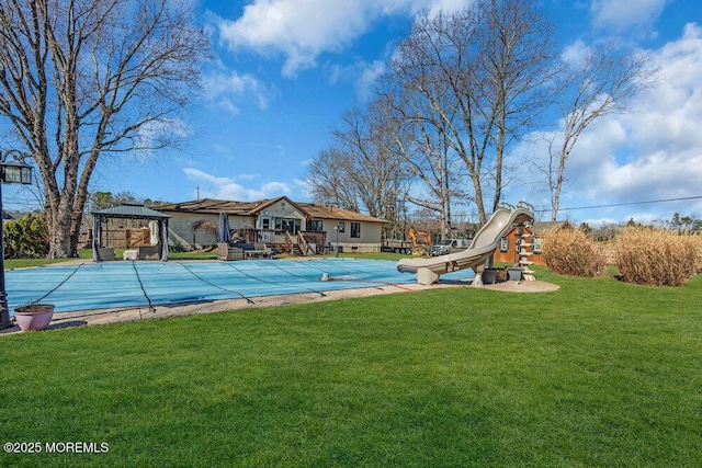 view of pool with a lawn, a covered pool, a gazebo, playground community, and a water slide