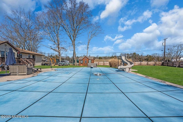 view of pool featuring a water slide, fence, a deck, a yard, and a patio area