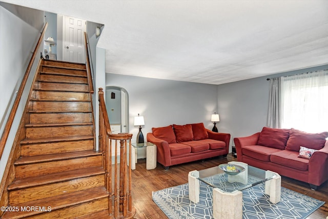 living room featuring arched walkways, wood finished floors, and stairs