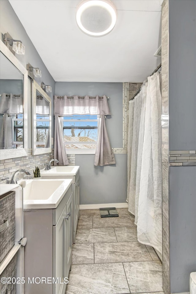 bathroom with vanity, baseboards, and backsplash