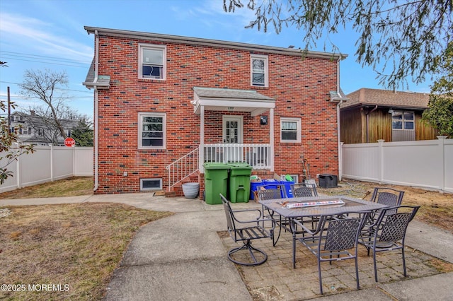 rear view of property featuring outdoor dining space, a patio area, a fenced backyard, and brick siding