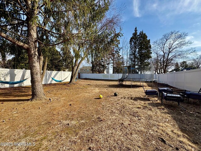 view of yard with a trampoline and a fenced backyard