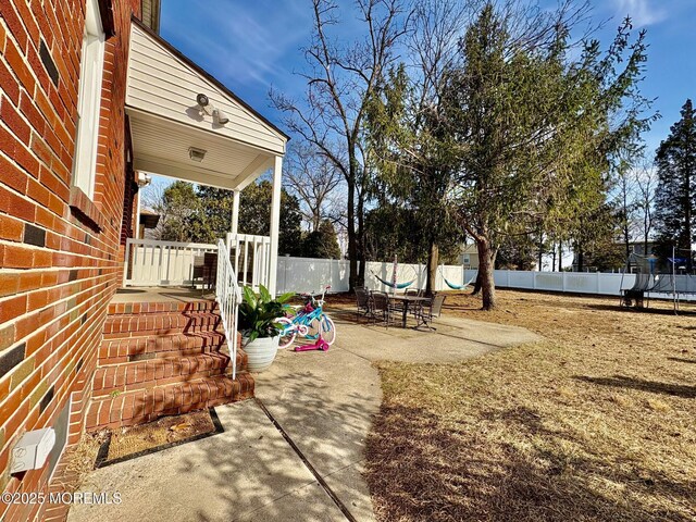 view of yard with a trampoline, a fenced backyard, and a patio area