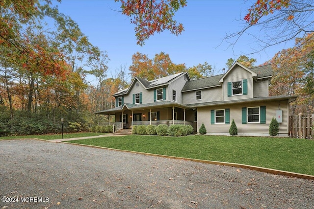 view of front facade featuring covered porch, a front lawn, and fence