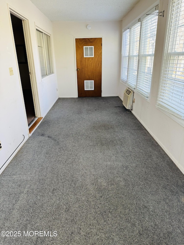 empty room with visible vents, plenty of natural light, a textured ceiling, and an AC wall unit